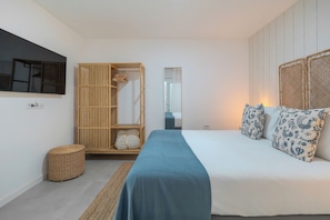 A bedroom with a bed, a wardrobe, a mirror, and a small round wicker basket. - Cozy Apartment Rental in Guargacho, Spain - Ideal Family Stay (Arona)