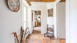 Un pasillo con una silla, un muro con un plato decorativo y una puerta.