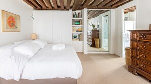 Un dormitorio con cama, cómoda, estantería y espejo.