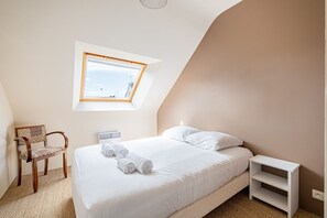 Een slaapkamer met dakraam, een bed, een stoel en een nachtkastje.