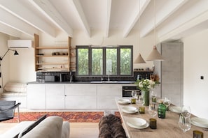 Een moderne keuken met een centraal kookeiland, inbouwplanken en een eethoek met een tafel voor zes personen.