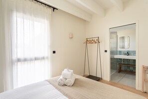 Een hotelkamer met een bed, een badkamer met een spiegel en een handdoekrek.