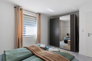 Un dormitorio con cama, espejo y armario.