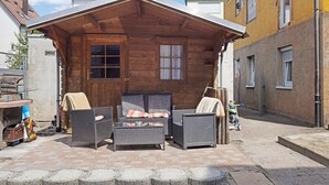 Ein Holzhaus mit Kamin, Korbmöbeln und Blick auf die Straße.