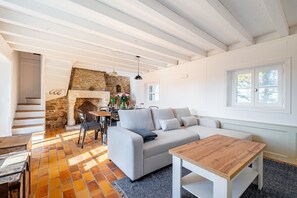 Ein Wohnzimmer mit Kamin aus Stein, einer Couch, einem Holztisch und einer Treppe zu einem anderen Raum.