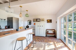 Een keuken met een houten aanrecht, barstoelen, een witte kast en een bank.