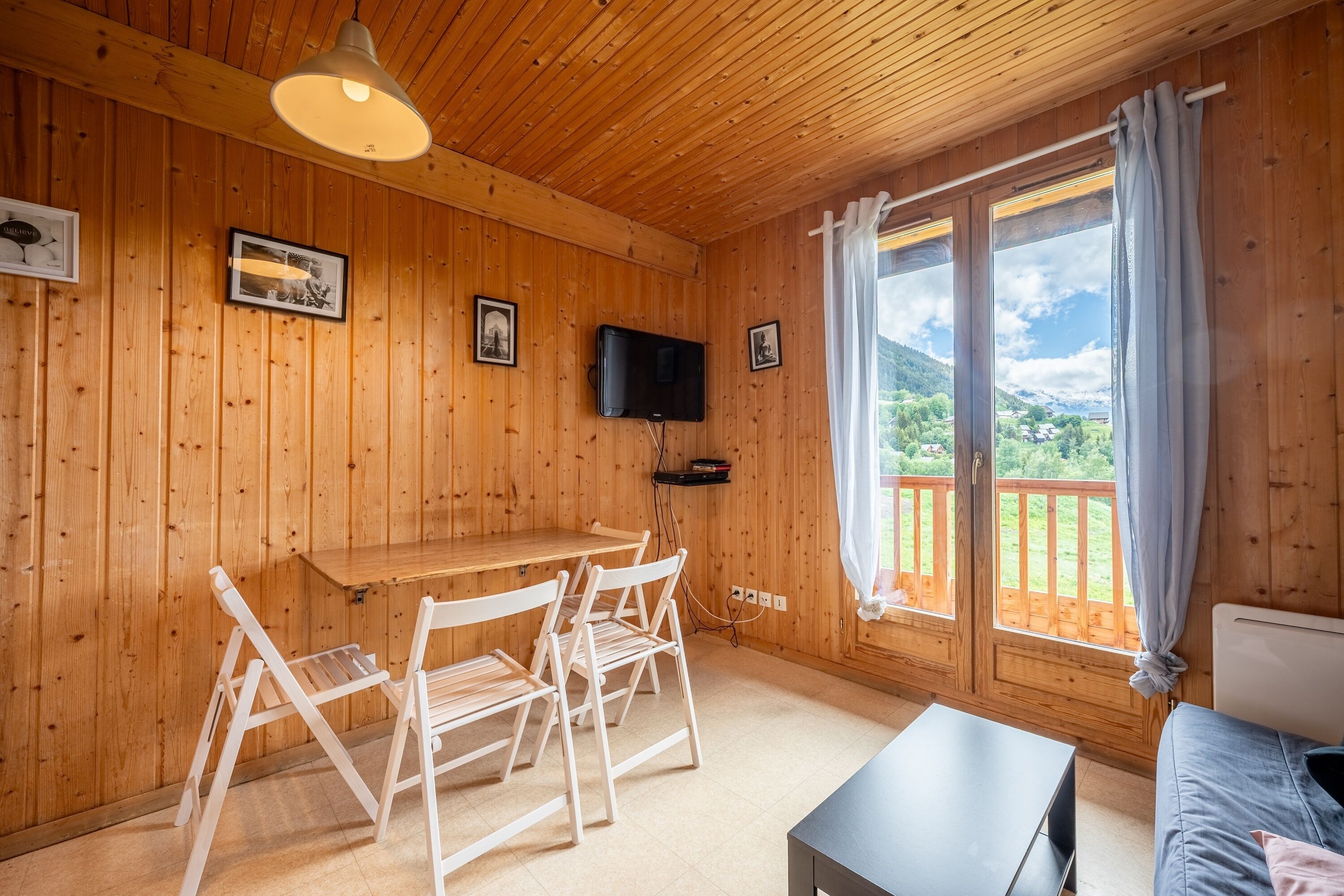 Ein Holzinterieur mit einem Tisch, Stühlen, einem Fernseher und einem Fenster mit Blick.