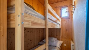Kerrossängyllä varustettu huone, jossa on puuseinät ja pieni ikkuna.