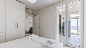 A bedroom with a bed, a wardrobe, an air conditioning unit, and a balcony with a view.