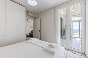 Ein Schlafzimmer mit Bett, Kleiderschrank, Klimaanlage und einem Balkon mit Blick.