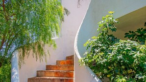 Eine Treppe mit Backsteinstufen führt zu einer weißen Wand, einem Briefkasten und grünem Grünwerk.