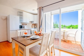 A modern kitchen with white cabinets, a dining table with chairs, and a balcony with a view. - D9 Quinta do Paraiso (Lagoa)