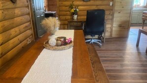 A wooden dining table with a woven placemat, a vase with dried pampas grass, and decorative items.