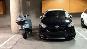 Eine Tiefgarage mit einem schwarzen Auto und einem Roller.
