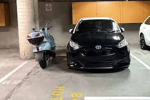 Eine Tiefgarage mit einem schwarzen Auto und einem Roller.