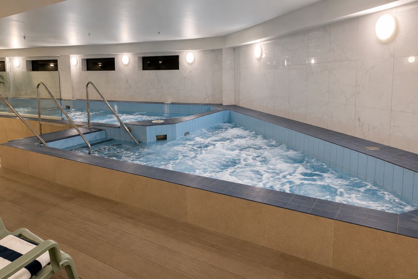 A hot tub with a wooden floor and a tiled wall.