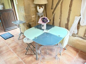 A small dining area with a glass table, two chairs, a lamp, and a vase with flowers. - Fontguilleres Vacation Rental (Rives)