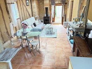 A rustic interior with a stone wall, a wooden table with chairs, a sofa, and a fireplace. - Fontguilleres Vacation Rental (Rives)