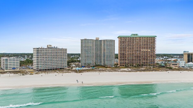 A beachfront hotel with multiple high-rise buildings, a sandy beach, and clear turquoise waters. - Gulf View Condo at Dunes of Panama with Pool (Panama City Beach)