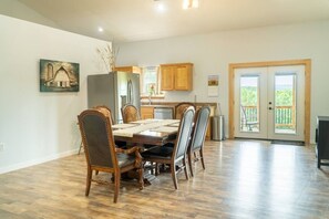 A dining area with a wooden table and chairs, a kitchen with wooden cabinets, and a balcony with a view. - Secluded Ranch Stay w/ Views | 2BR/2BA (Walnut Shade)