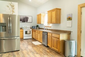A modern kitchen with wooden cabinets, stainless steel appliances, and a wooden floor. - Secluded Ranch Stay w/ Views | 2BR/2BA (Walnut Shade)