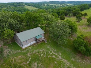 An aerial view of a single-story building with a green roof, surrounded by lush greenery and trees. - Secluded Ranch Stay w/ Views | 2BR/2BA (Walnut Shade)