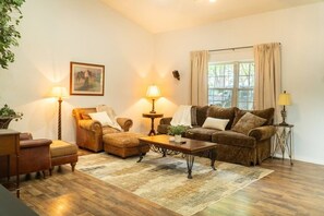 A living room with a sofa, armchair, ottoman, coffee table, and two lamps. - Secluded Ranch Stay w/ Views | 2BR/2BA (Walnut Shade)