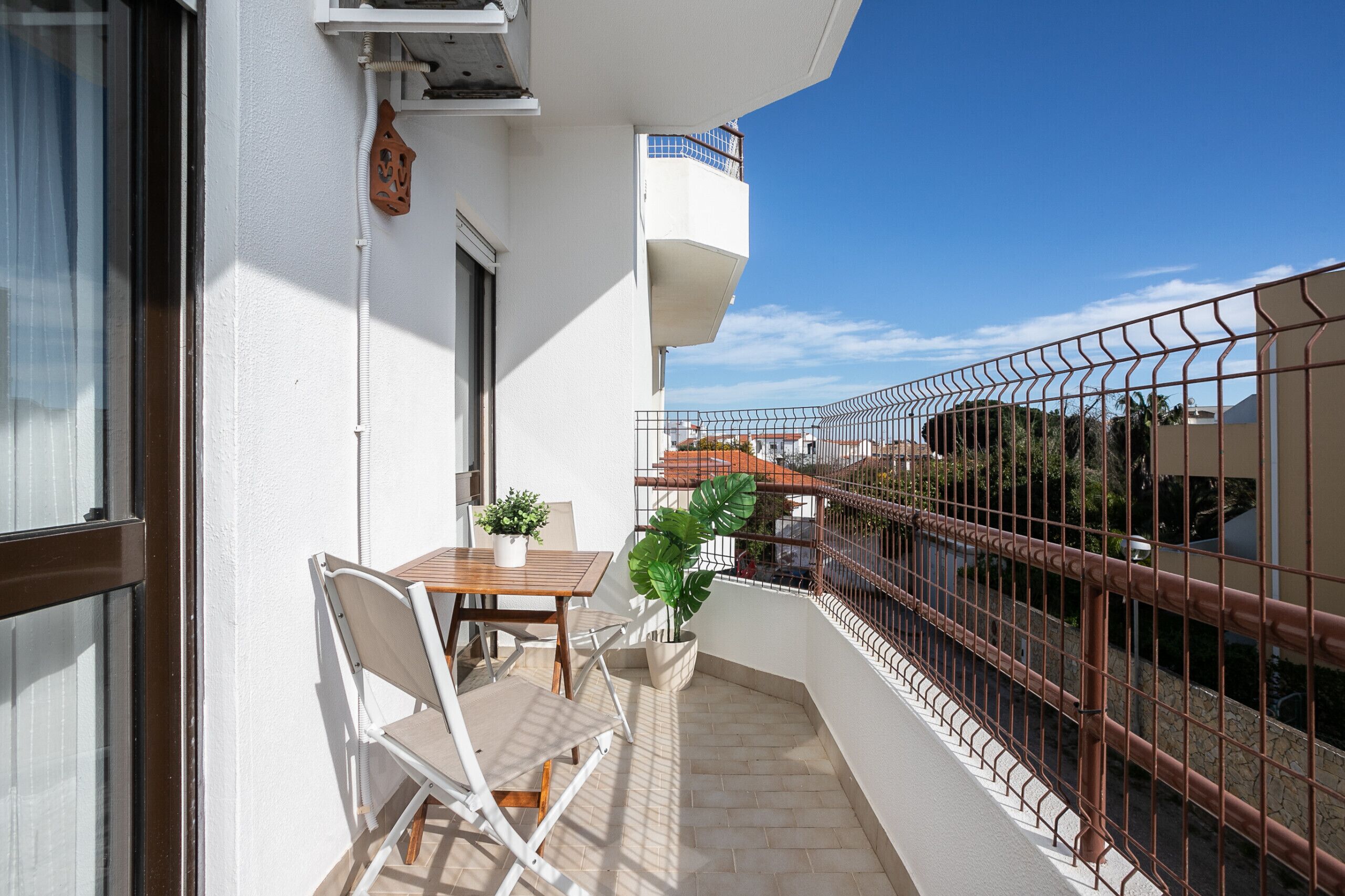Ein Balkon mit Tisch, Stühlen, einem Blumentopf und einem Metallgeländer.