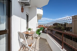 Ein Balkon mit Tisch, Stühlen, einem Blumentopf und einem Metallgeländer.