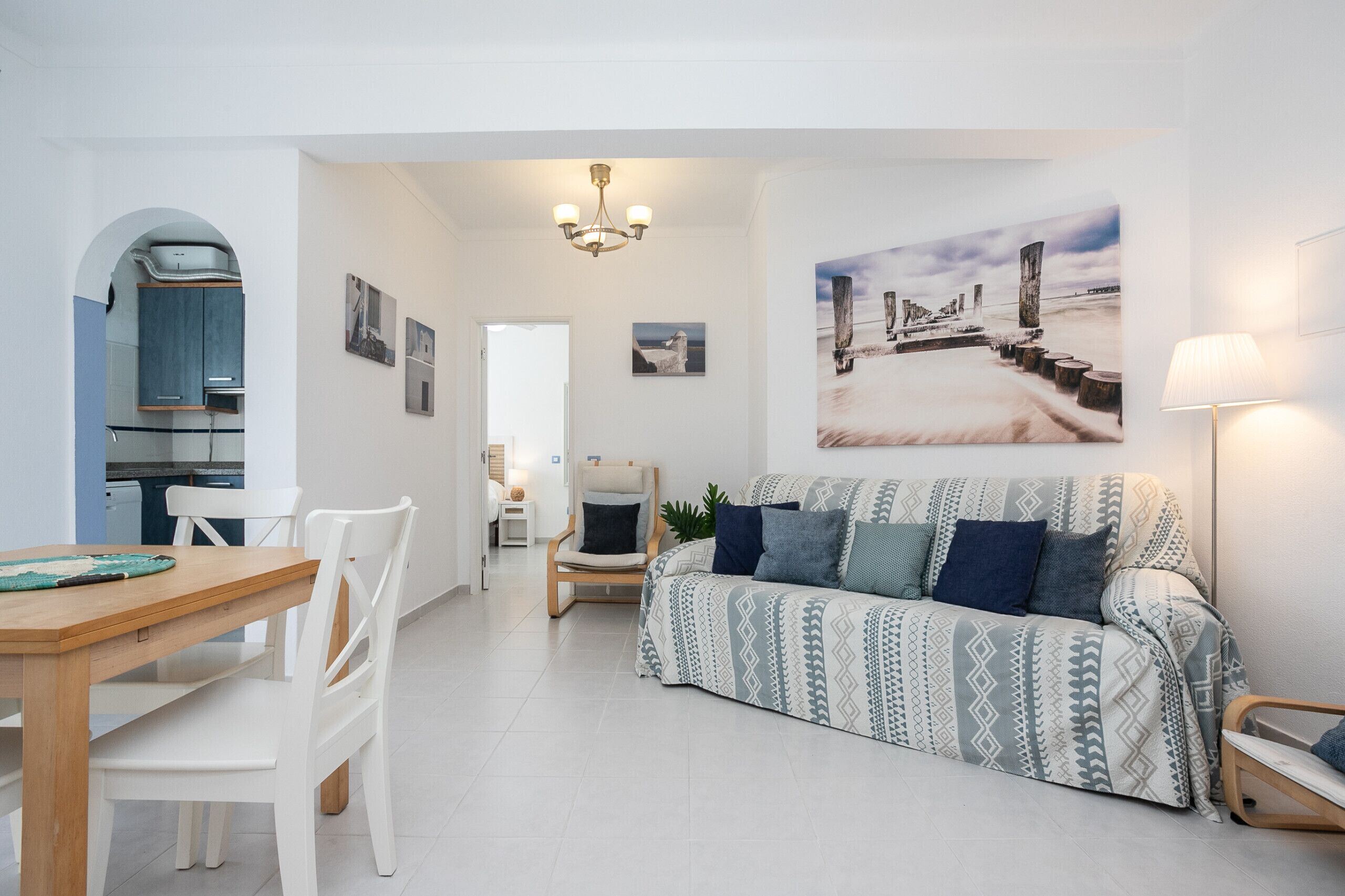 Ein modernes Wohnzimmer mit Sofa, Esstisch und Stühlen, einer Küchenzeile und einem Flur, der in einen weiteren Raum führt.