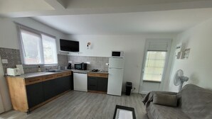 A compact kitchen with a microwave, toaster, and refrigerator. There is a small dining table and a sofa in the living area. - Pom Kanel Vacation Rental with Unobstructed Views (Sainte-Anne)