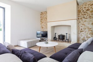 A modern living room with a fireplace, a television, and a sofa.