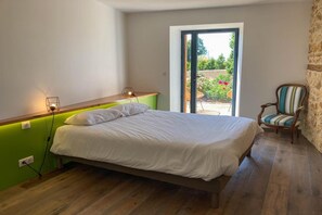 A bedroom with a bed, a desk, a chair, and a view through a door.