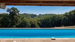 Une piscine avec vue sur une colline boisée.