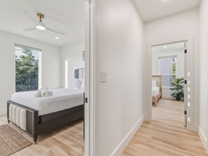 Ein modernes Schlafzimmer mit einem Bett, einem Deckenventilator, einem großen Fenster und Blick ins Freie.