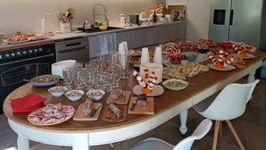A modern kitchen with a long island counter, equipped with various food items and glassware, and a built-in oven. - Il Casale: A Charming Country House in the Monferrato Hills (Colcavagno)