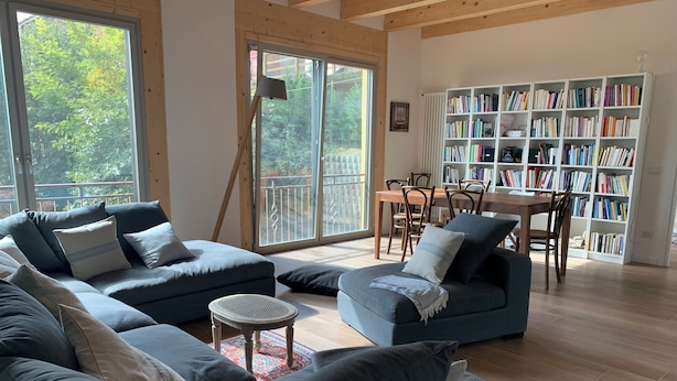 A spacious living room with a large sectional sofa, a small round table, and a bookshelf filled with books. - Il Casale: A Charming Country House in the Monferrato Hills (Colcavagno)