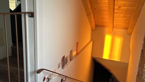 A staircase with wooden steps, a metal handrail, and a white wall with a shelf holding items. - Il Casale: A Charming Country House in the Monferrato Hills (Colcavagno)