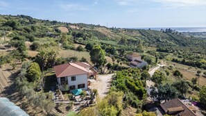 A rural house with a tiled roof, surrounded by greenery and hills. - Villa Baronia (Stampella)