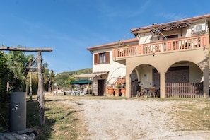 A building with a balcony, outdoor seating, and a gravel path. - Villa Baronia (Stampella)
