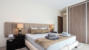 A modern bedroom with a large bed, two bedside tables with lamps, a headboard, and a wardrobe. - Villa Miradouro Do Sul by Marenssa (Moncarapacho)