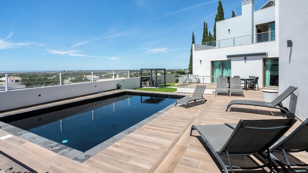 A rooftop pool with lounge chairs, a glass-enclosed dining area, and a view of the cityscape. - Villa Miradouro Do Sul by Marenssa (Moncarapacho)