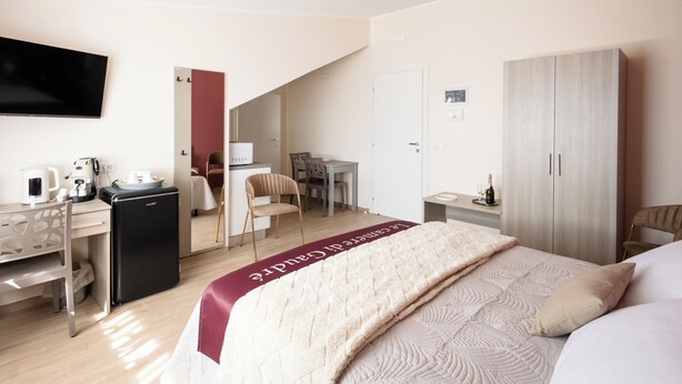 Habitación de hotel con cama, escritorio con computadora, televisor y minibar.