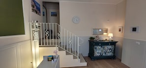 Un escalier avec des rampes blanches, une horloge, un miroir et un meuble ornĂ© dâun motif floral.