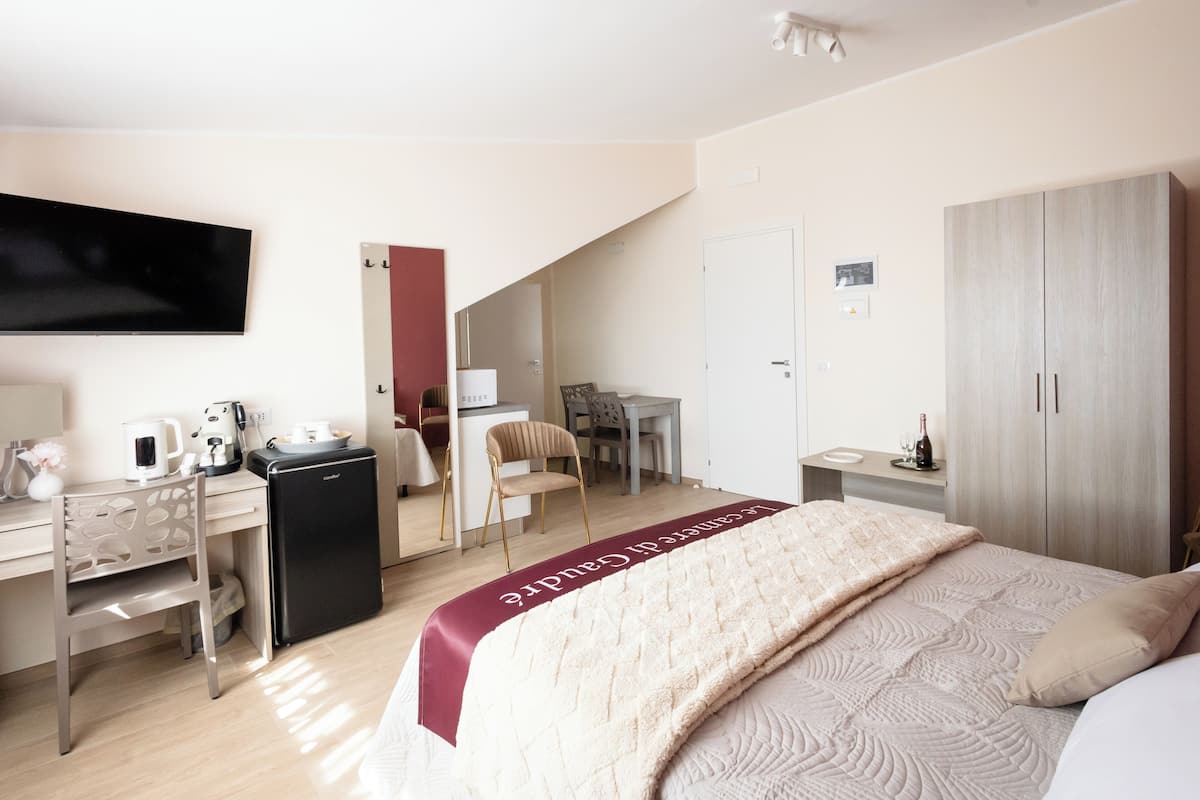 Ein Hotelzimmer mit einem Bett, einem Schreibtisch mit Computer, einem Stuhl, einem Fernseher und einem Kleiderschrank.