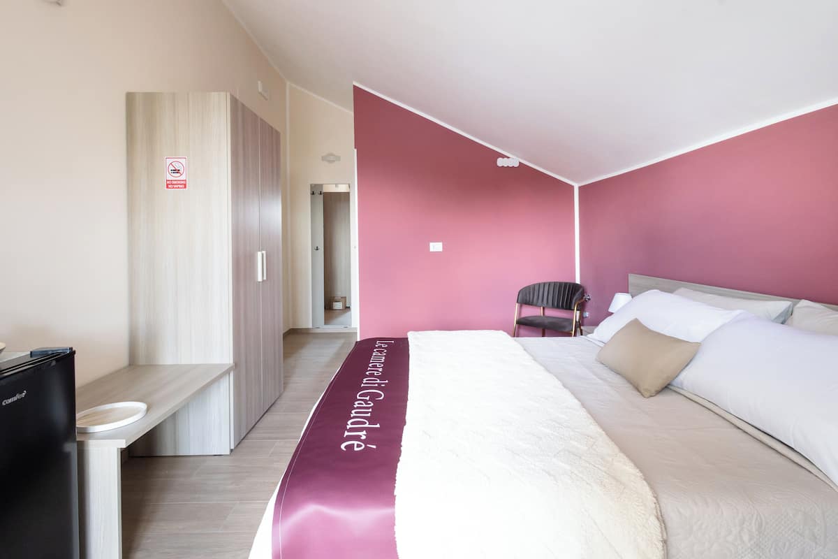 Ein Hotelzimmer mit Bett, Stuhl, Kleiderschrank und Schreibtisch mit Kaffeemaschine.