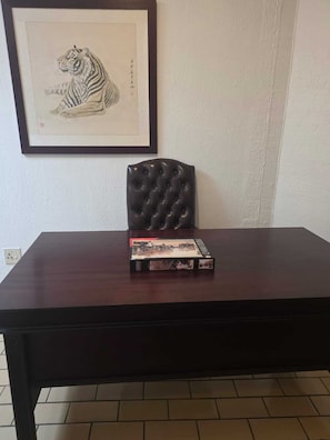 A dark wooden table with a framed tiger illustration on the wall behind it. - Sunny sanctuary in the heart of Gallo Manor (Sandton)