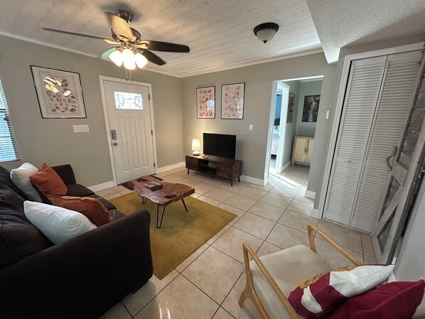 A living room with a sofa, coffee table, TV, and a ceiling fan. - The Native-Vintage Florida Vibe in the Oldest City (St. Augustine)