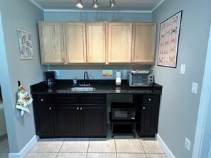 A kitchen with wooden cabinets, a sink, a toaster, and a microwave. - The Native-Vintage Florida Vibe in the Oldest City (St. Augustine)