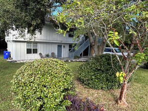 A two-story house with a front porch, a staircase, and a tree with green leaves. - The Native-Vintage Florida Vibe in the Oldest City (St. Augustine)